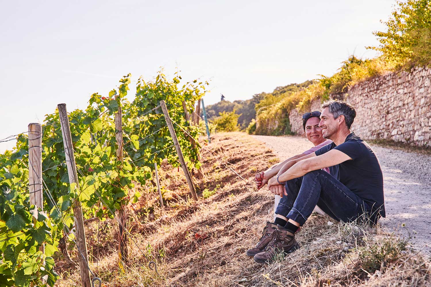 Zwei Wandernde sitzen auf dem Wanderweg in den Weinbergen